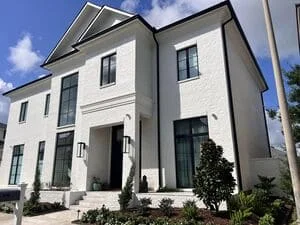 White two-story home with new gutter and downspout system installed along roofline