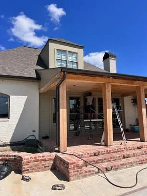 Cedar patio cover with installed gutters and downspouts on brick home addition