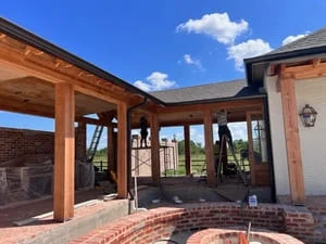 Seamless gutters installed on covered patio with wood beams and brick construction