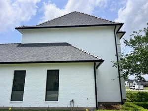 Black seamless gutters and downspouts installed on white two-story residential home