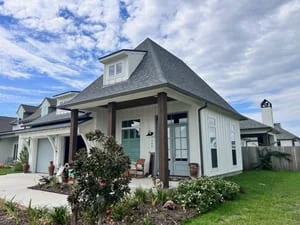 White farmhouse with new seamless gutters installed around mansard roof and home perimeter