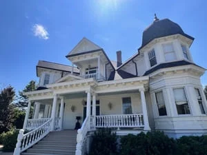 White Victorian home with gutter system installed along multiple roof lines and turrets
