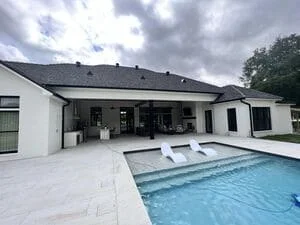 Seamless gutter installation on modern white residential home with pool area