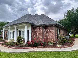 New gutters installed on brick and vinyl residential home with landscaping