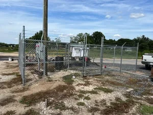 Chain-link fence with metal gate and posts installed around outdoor facility