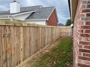 New wood privacy fence with vertical boards installed along residential backyard
