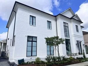 White farmhouse with installed gutters and downspouts on multi-level roof