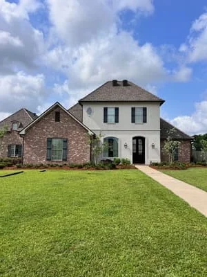 Two-story brick home with new gutter system installed on hip roof