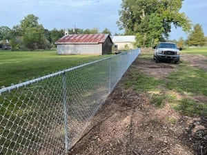 Galvanized chain-link fence installation with metal posts along residential property