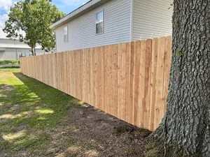 New cedar privacy fence with vertical boards installed along residential property