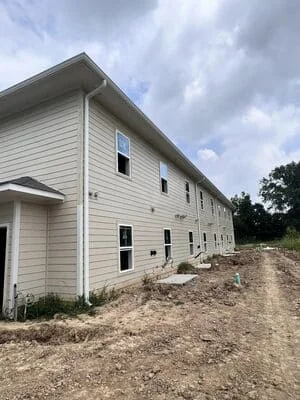 White vinyl-sided two-story home with installed gutters and downspouts during construction phase